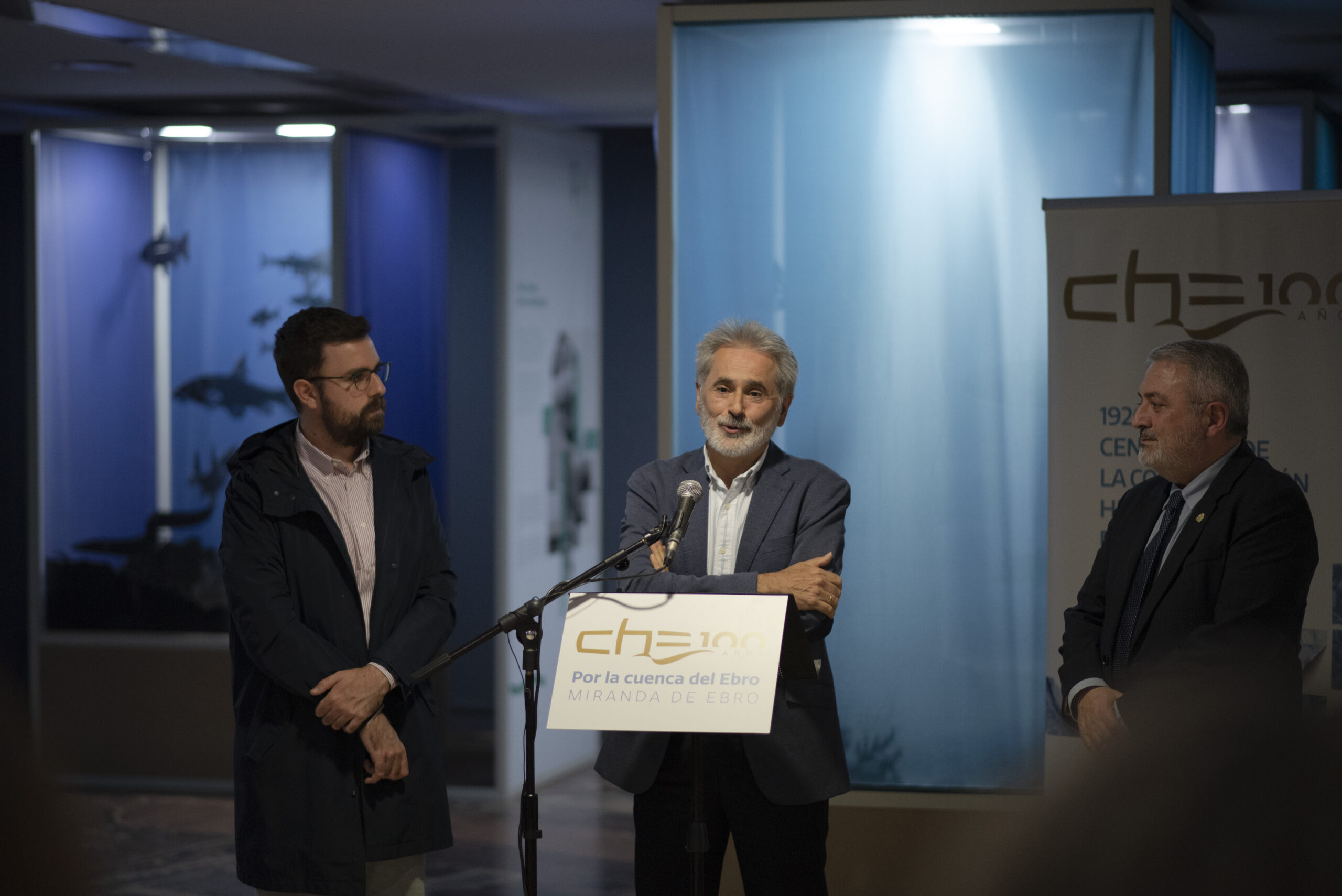 Javier San Román interviene en el acto inaugural de la exposición Por la cuenca del Ebro en Miranda de Ebro, acompañado por Pablo Gómez Ibáñez, primer teniente de alcalde, y Pedro L. de la Fuente Fernández, subdelegado del Gobierno en Burgos.